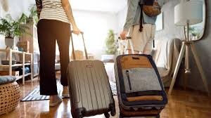 Pareja caminando con maletas en un apartamento de vacaciones. Título: Llegada a un Apartamento de Vacaciones. Couple walking with suitcases into a vacation apartment.. Rua, nrua, nra, registro de alquiler único ventanilla, teresa gestora de alquiler vacacional, registradores.
