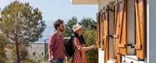 Pareja entrando a una casa de alquiler turístico con maletas EN: Couple entering a vacation rental house with suitcases. Rua, nrua, nra, registro de alquiler único ventanilla, teresa gestora de alquiler vacacional, colegio de registradores, turismo, vivienda uso turistico, vut, Airbnb, booking. Vbro. Pms.