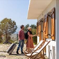 Pareja entrando a una casa de alquiler turístico con maletas EN: Couple entering a vacation rental house with suitcases. Rua, nrua, nra, registro de alquiler único ventanilla, teresa gestora de alquiler vacacional, colegio de registradores, turismo, vivienda uso turistico, vut, Airbnb, booking. Vbro. Pms.