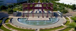 Número de Registro de Alquiler NRUA. Jornadas en la Universidad de Alicante. Panoramic view of a university campus with a central fountain and metallic structure.