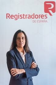 Rocío Perteguer: Nuevo Número de Registro Único Protege a Propietarios e Inquilinos. Professional woman posing in front of the Registradores de España logo.