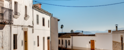 Rua, nrua, nra, registro de alquiler único ventanilla, teresa gestora de alquiler vacacional, colegio de registradores, turismo, vivienda uso turistico, vut, Airbnb, booking. Vbro. Pms. Calle empedrada en un pueblo rural con casas blancas y paisaje montañoso al fondo. Imagen de una calle empedrada en un pueblo rural, con casas blancas de estilo tradicional. Cobblestone street in a rural village with white houses and mountainous landscape in the background.